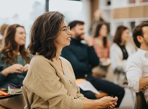Creative Writing Workshops Smiling woman learning in classroom setting.